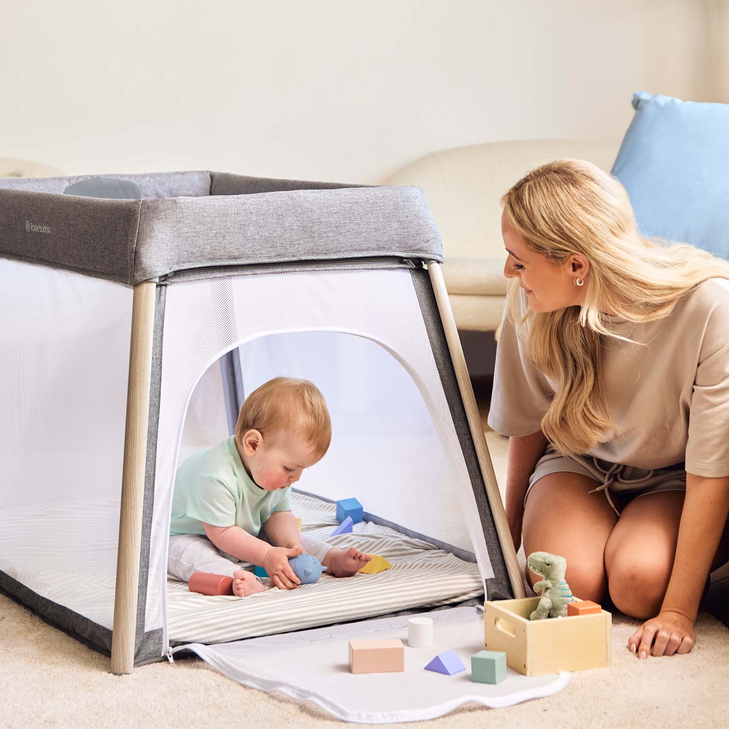 happy mom looking at her baby playing inside the Ickle Bubba Scout 2-in-1 Travel Cot and Playpen