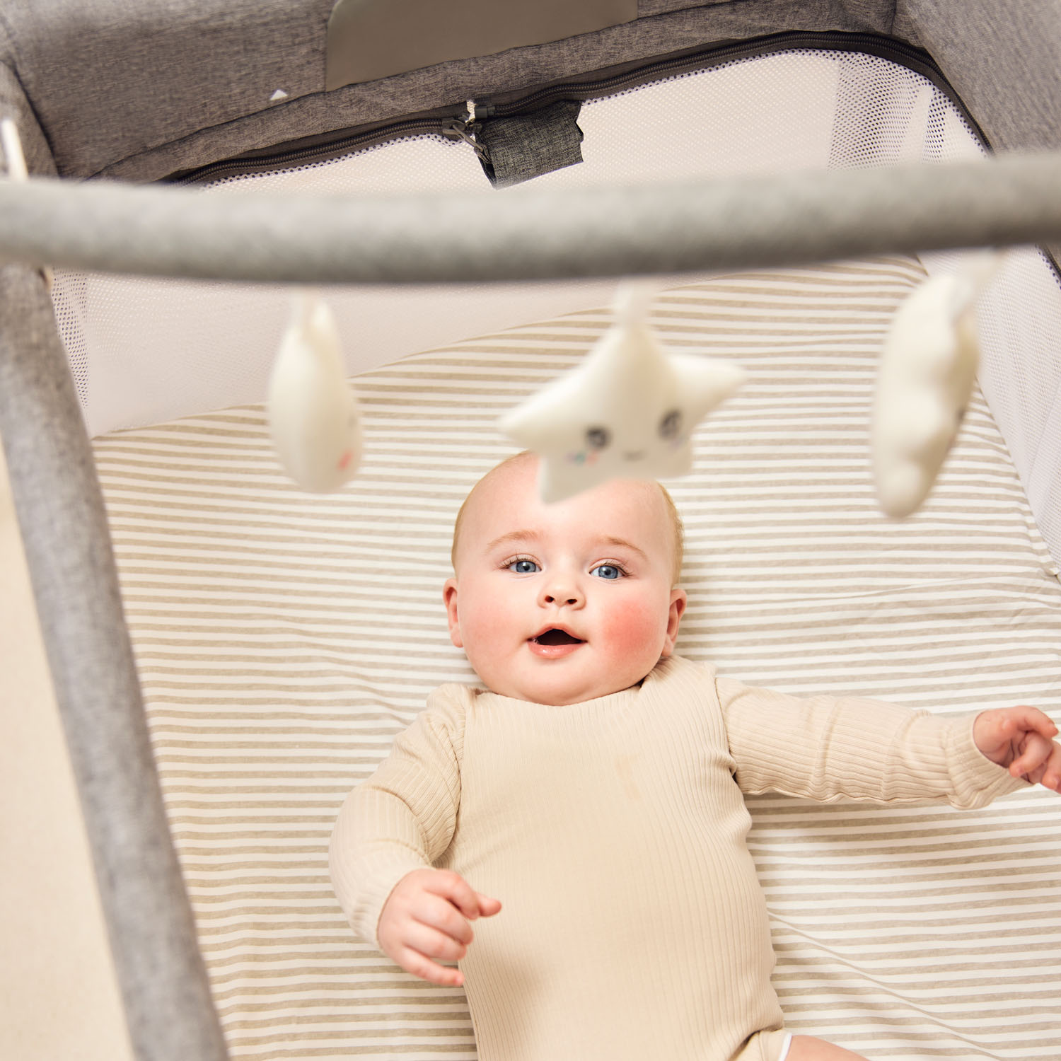 engaged baby looking at the hanging toys in the Ickle Bubba Scout 3-in-1 Travel Crib, Cot and Playpen