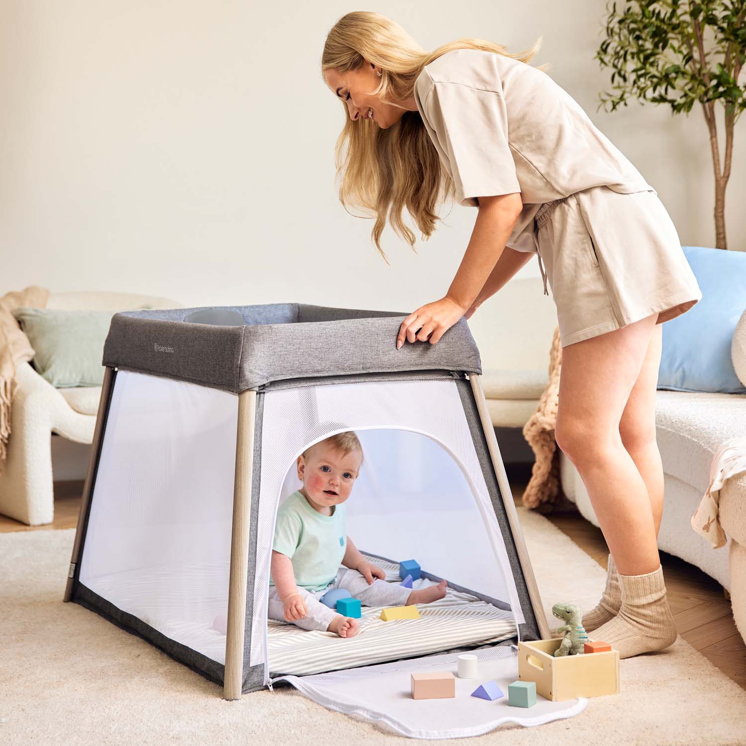 happy mom looking at her baby playing inside the Ickle Bubba Scout 3-in-1 Travel Crib, Cot and Playpen