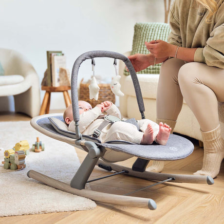 Baby lying in Ickle Bubba Stella Rocker set to the lowest recline position beside a mom