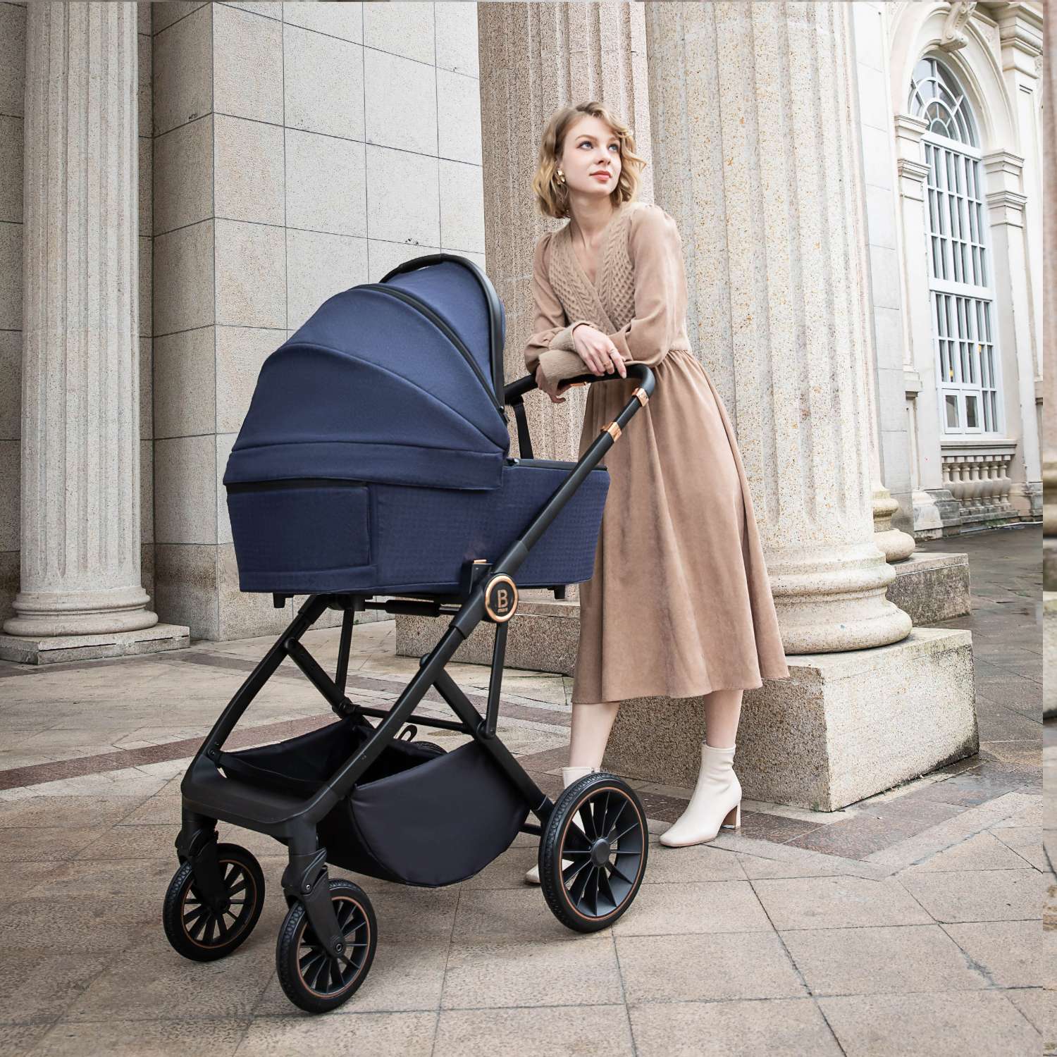 a woman pushing a Babymore Chia with carrycot in Midnight Blue variant