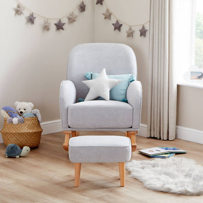 A straight-on front shot of Babymore Freya Nursing Chair with Footstool Set in Grey colour in a corner of a nursery room with a basket full of plush toys beside it.