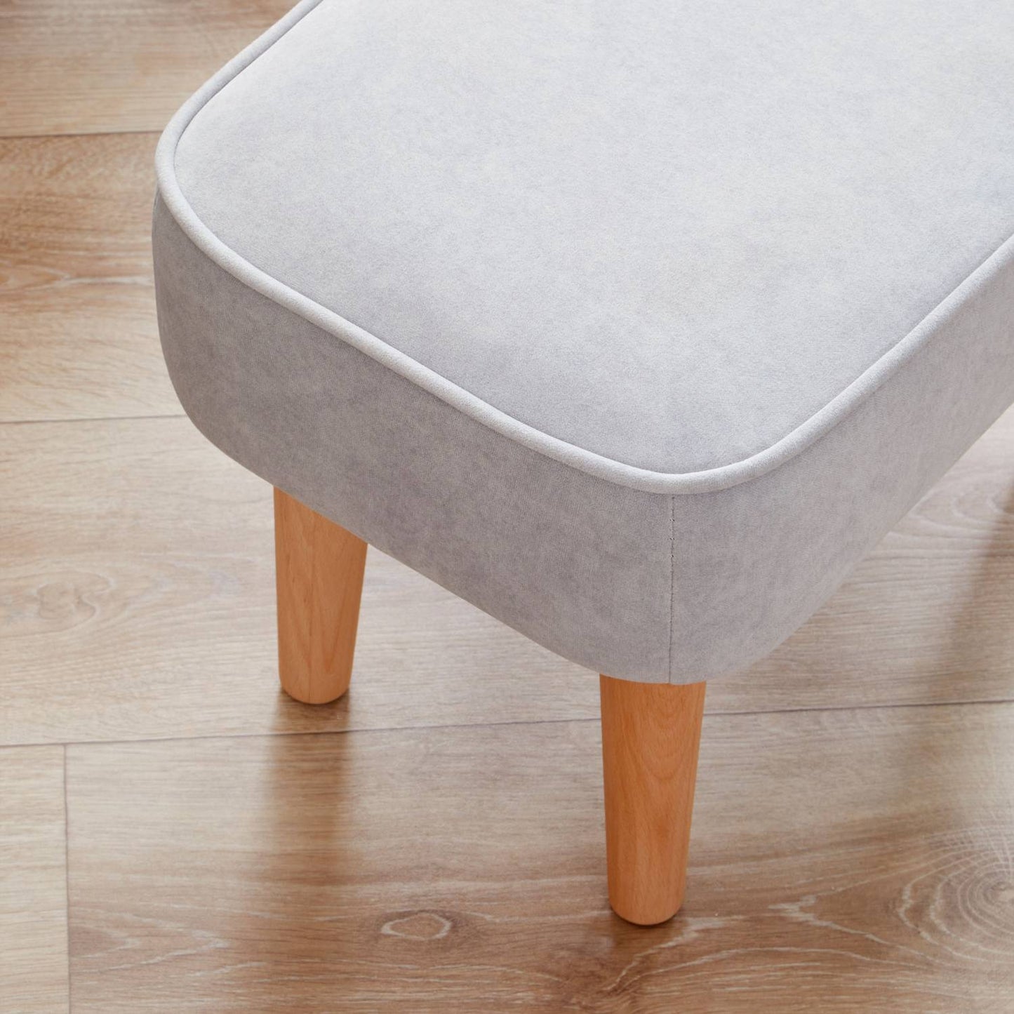 A close-up shot of the Babymore Freya Footstool in Grey color showing the natural solid beech wood legs.