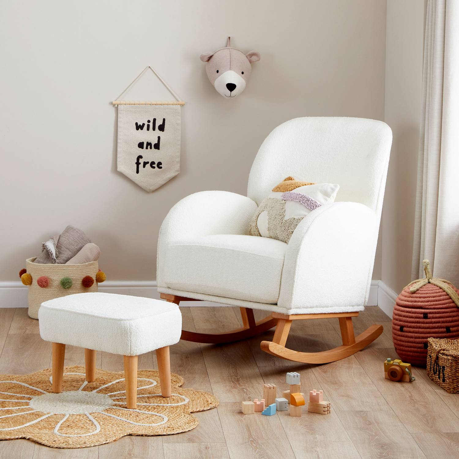 An angled shot of Babymore Freya Nursing Chair with Stool Set in Off White Boucle colour in a corner of a nursery room with some wooden toys on the floor.