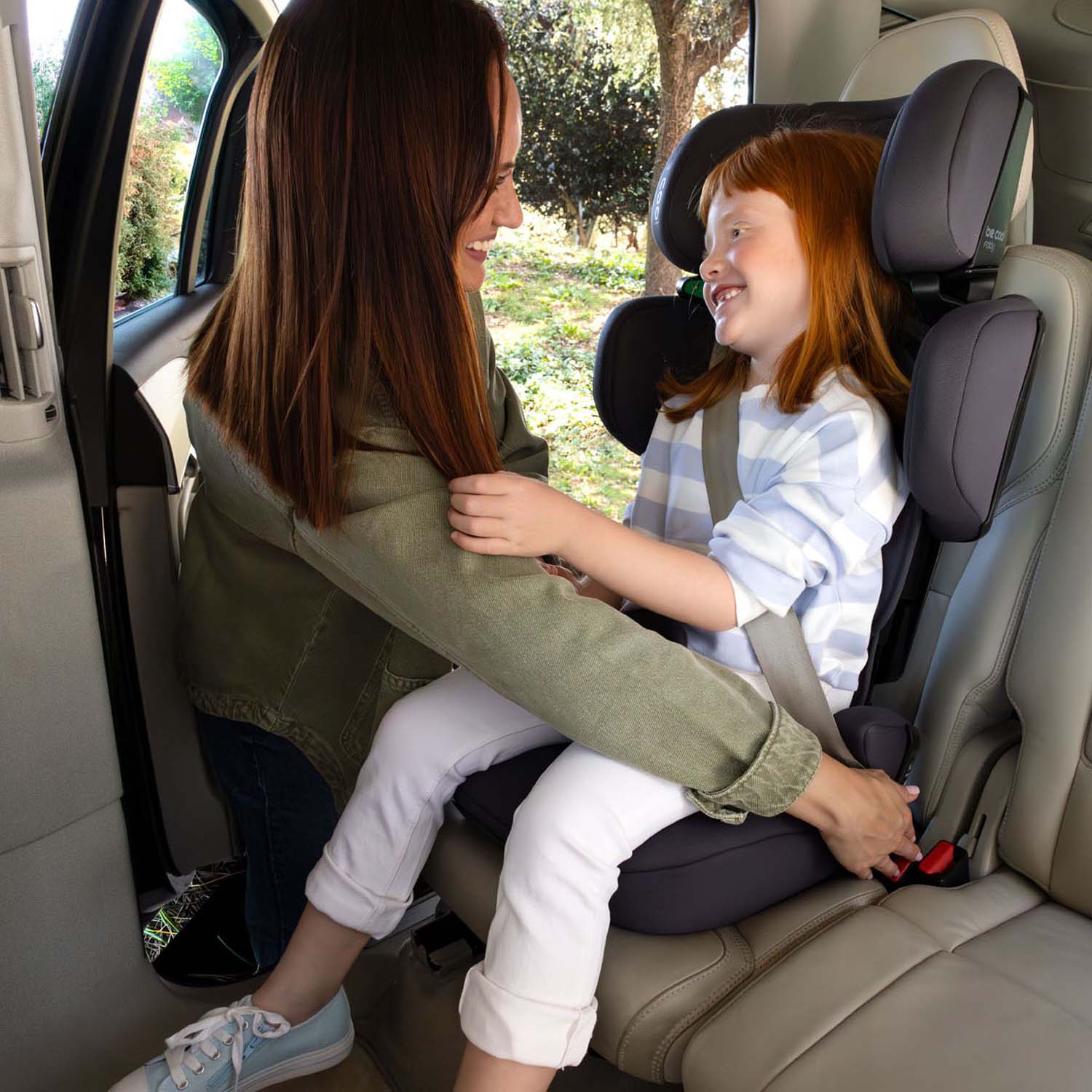 Mom adjusting the seat belt on her daughter as she sits in Be Cool Foldy i-Size Car Seat