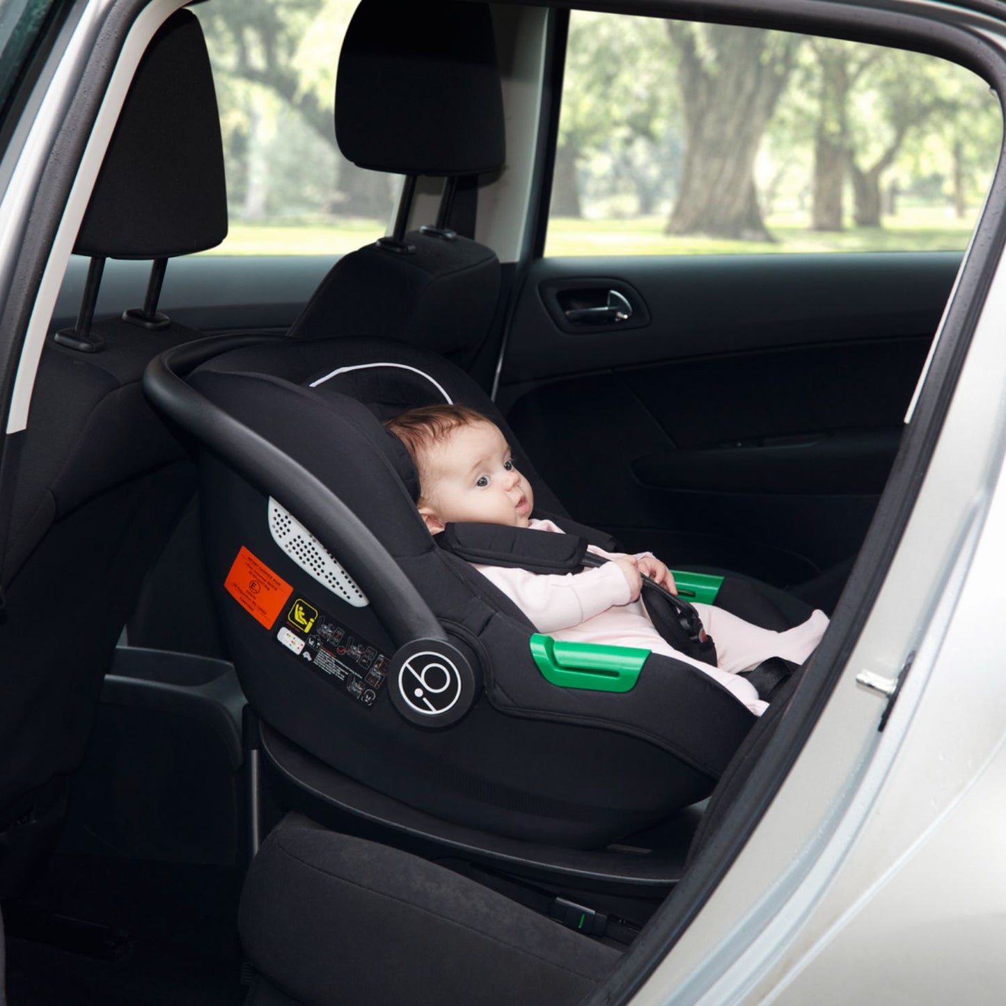 A baby in an Ickle Bubba Cirrus i-Size Car Seat attached inside a car