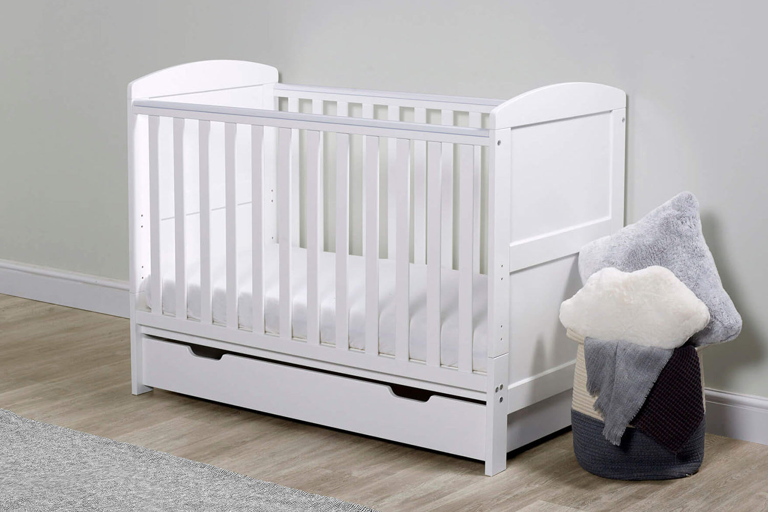 A white Ickle Bubba Coleby Mini 2-in-1 Cot Bed with Under Drawer in a nursery room