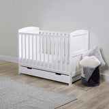 A white Ickle Bubba Coleby Mini 2-in-1 Cot Bed with Under Drawer and Premium Sprung Cot Mattress in a nursery room