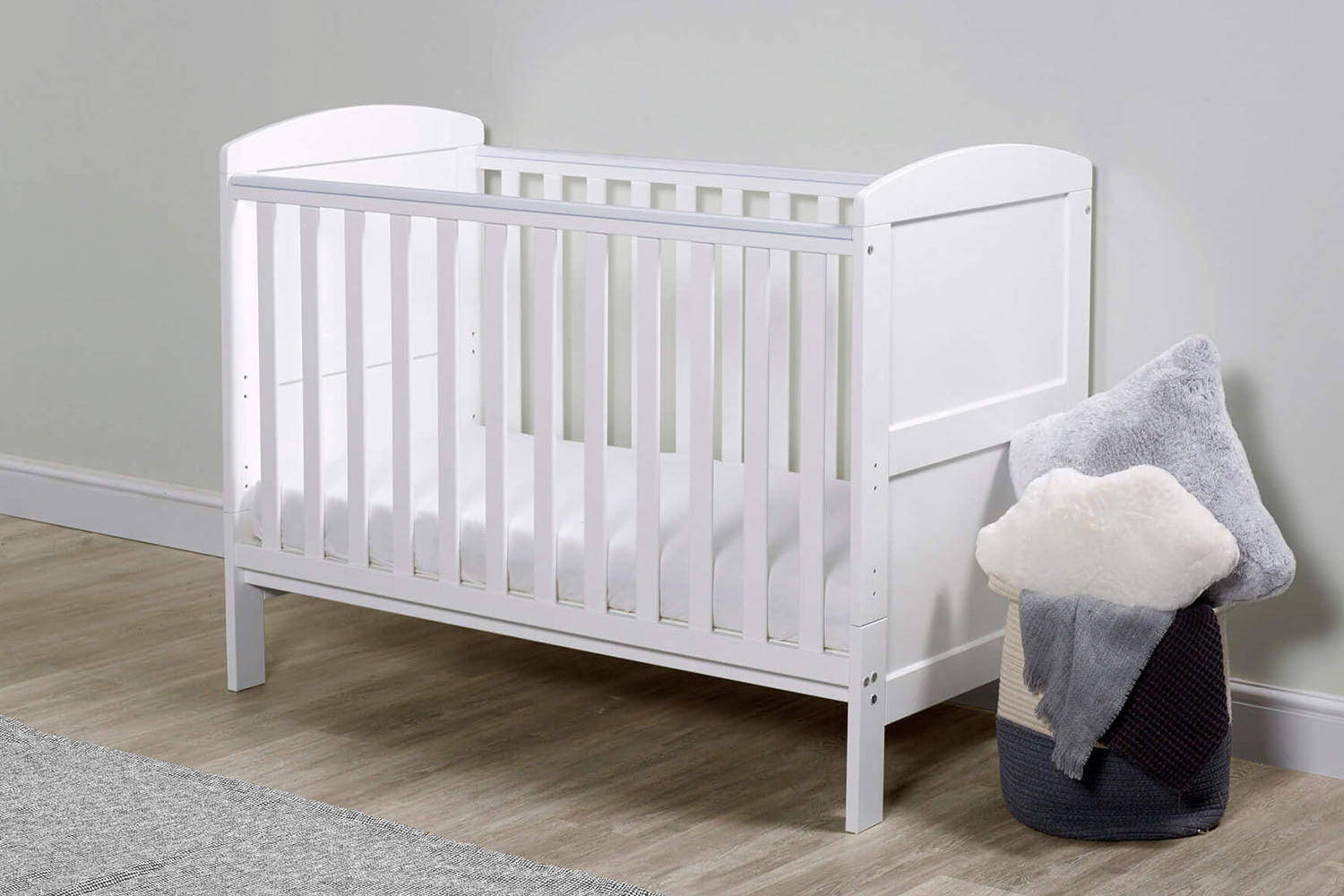 A white Ickle Bubba Coleby Mini 2-in-1 Cot Bed in a nursery room