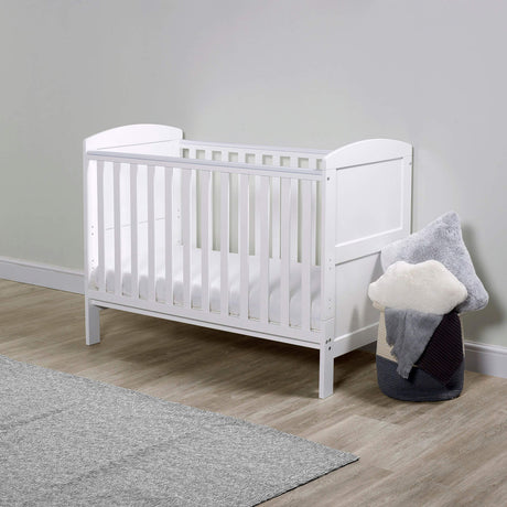 A white Ickle Bubba Coleby Mini 2-in-1 Cot Bed with All Seasons Premium Pocket Sprung Mattress in a nursery room