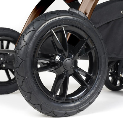Close-up shot of all-terrain wheels in Ickle Bubba Stomp Luxe Pushchair in Midnight black colour with bronze chassis and tan handle