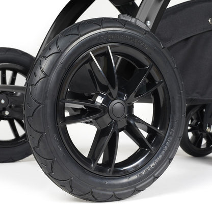 Close-up shot of all-terrain wheels in Ickle Bubba Stomp Luxe Pushchair in Midnight black colour with tan handle