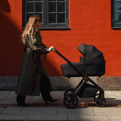 Woman walking while pushing a Venicci Claro Pram in Noir black colour