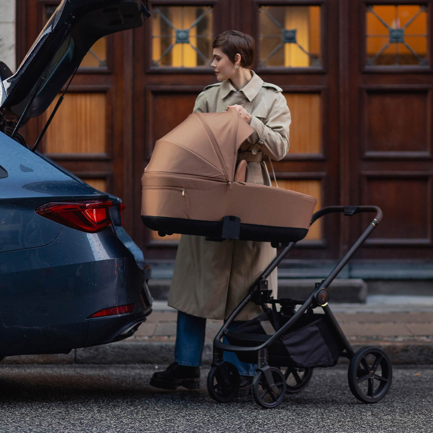 A mother lifting a Caramel Venicci Claro Carrycot to store in her car's boot