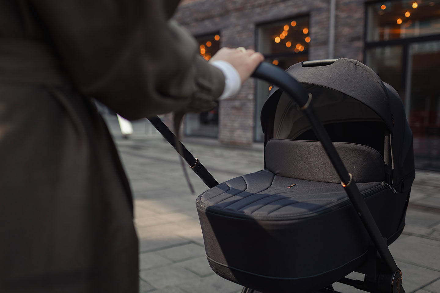 A person pushing a Venicci Claro 3-in-1 Travel System in Noir black color