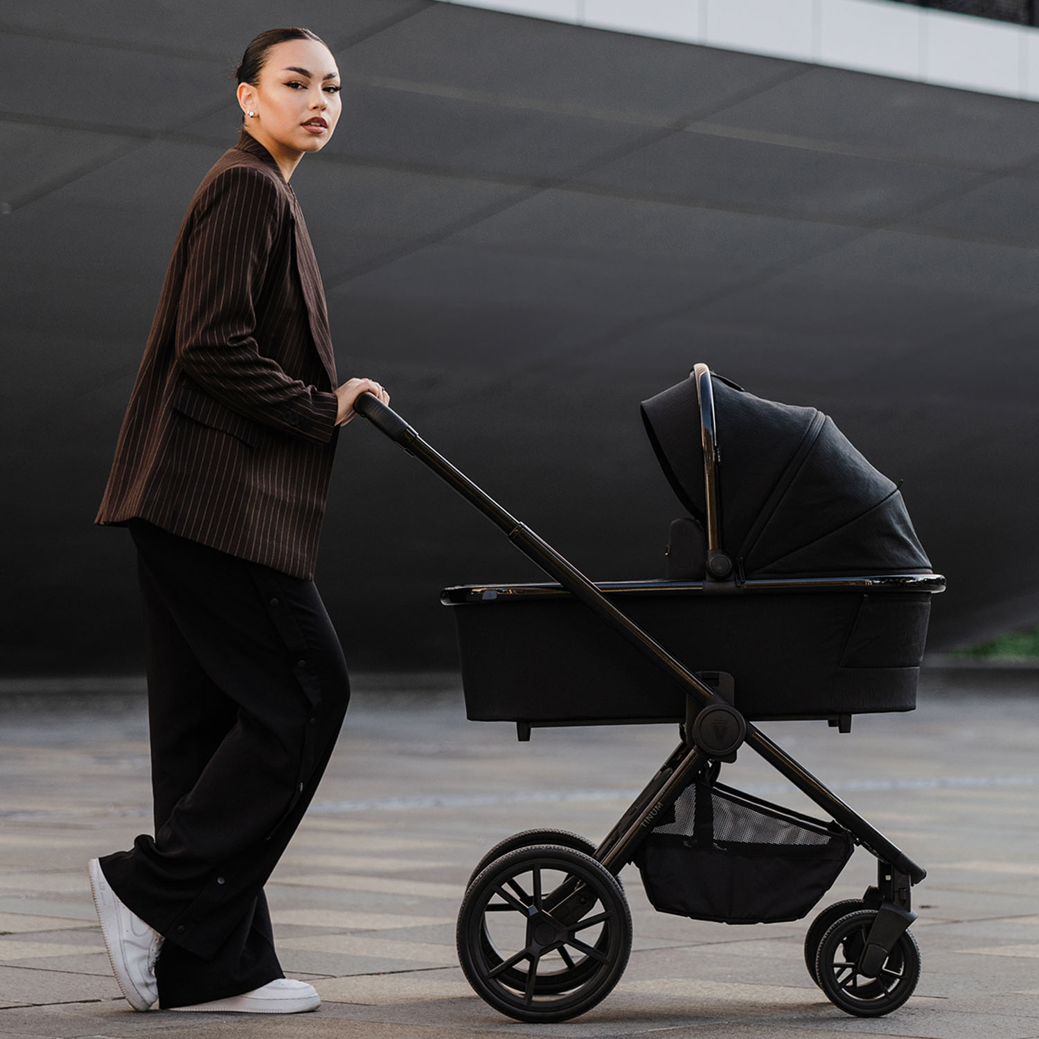 Woman pushing the Venicci Tinum Edge SE Pram in stylish Raven black colour