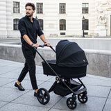 A man pushing a Venicci Upline 2-in-1 Pram in All Black colour