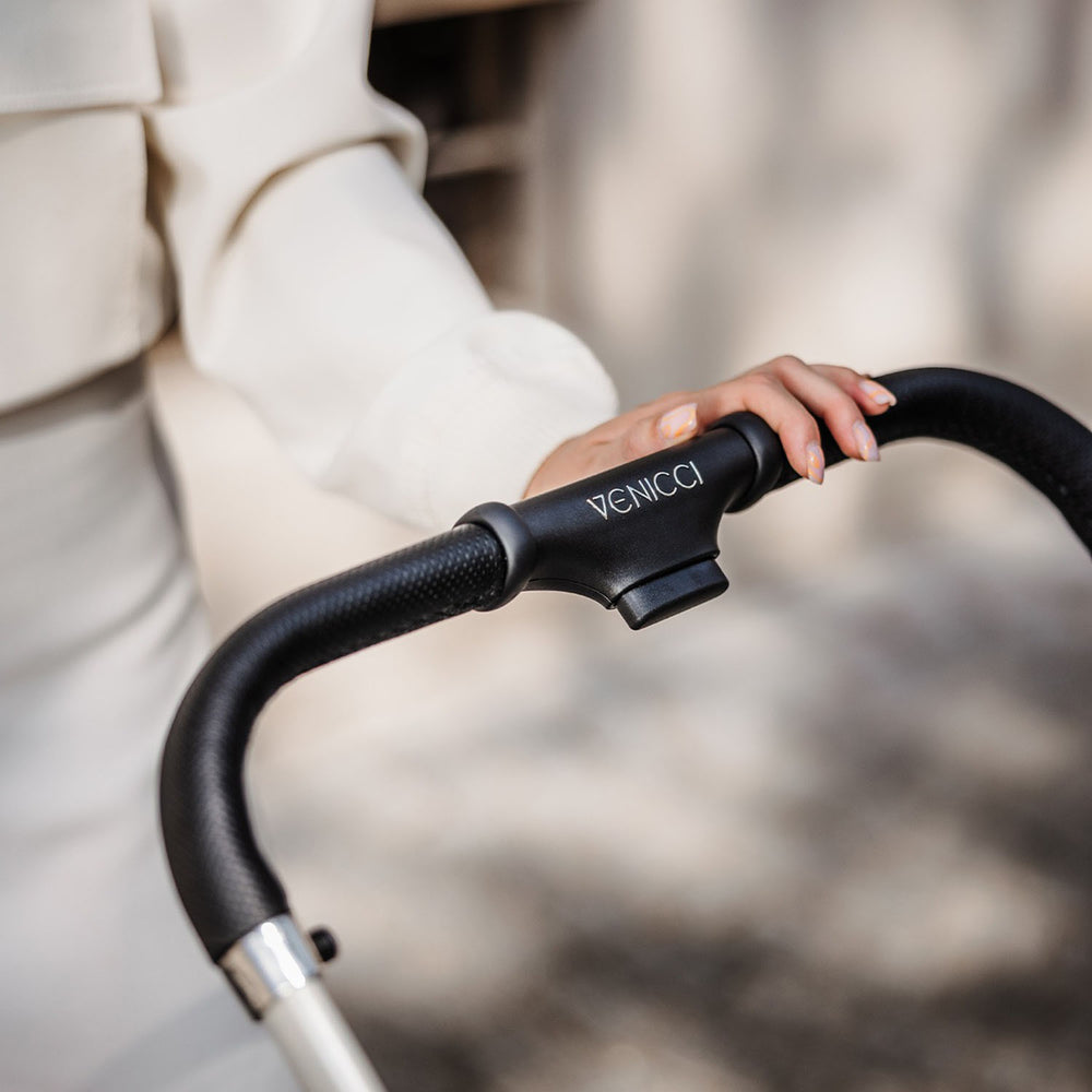 A woman holding the handle bar of Venicci Upline Pram in Moonstone colour