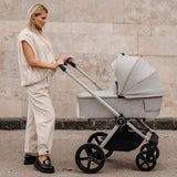 A woman pushing a Venicci Upline 2-in-1 Pram in Moonstone colour