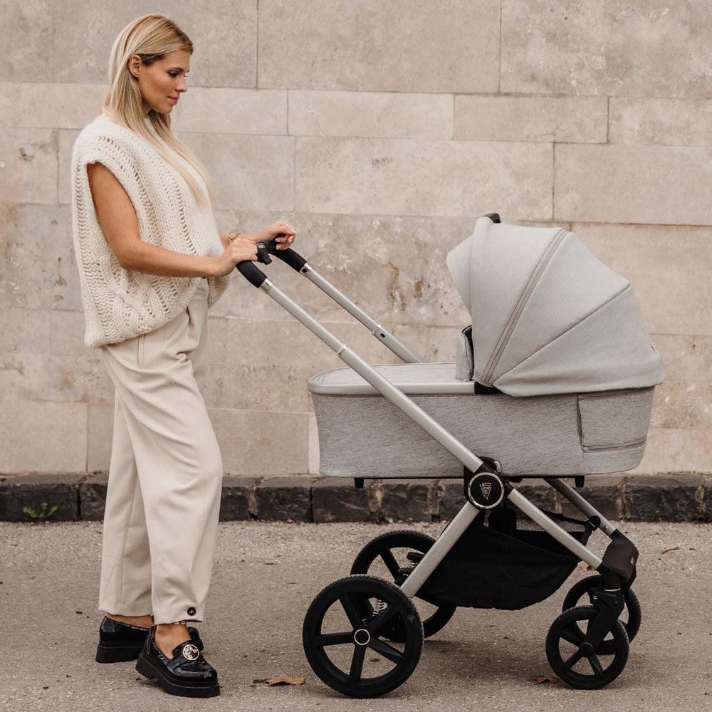 A woman pushing a Venicci Upline 2-in-1 Pram in Moonstone colours