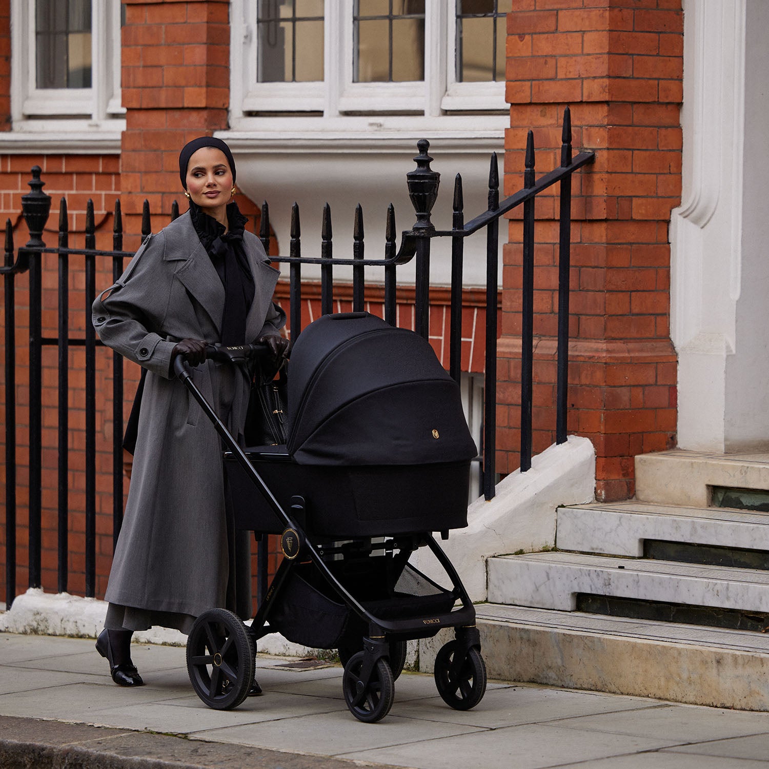 A mother walking and pushing a Venicci Upline 2 Pram in All Black colour